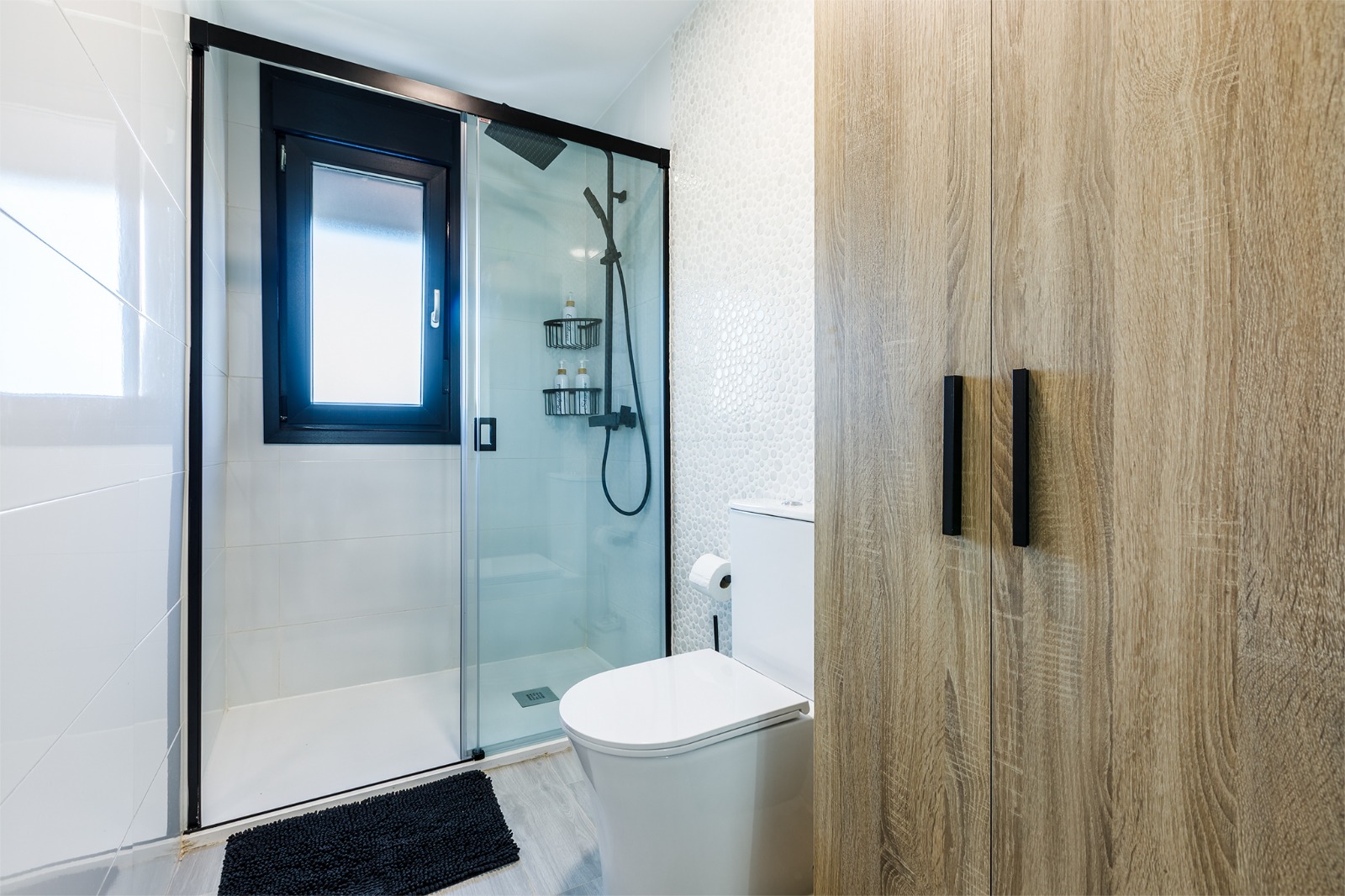 Baño con ducha y armario de madera