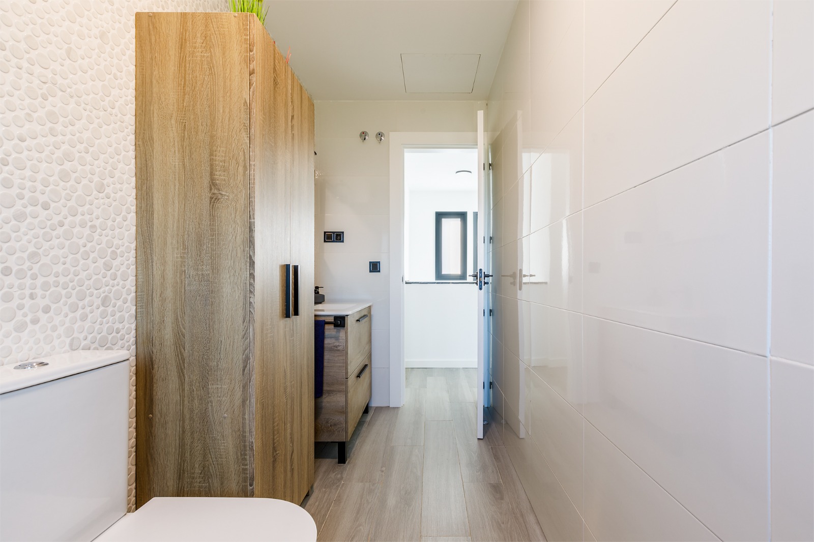 Baño con pared de mosaico, columna de madera e inodoro