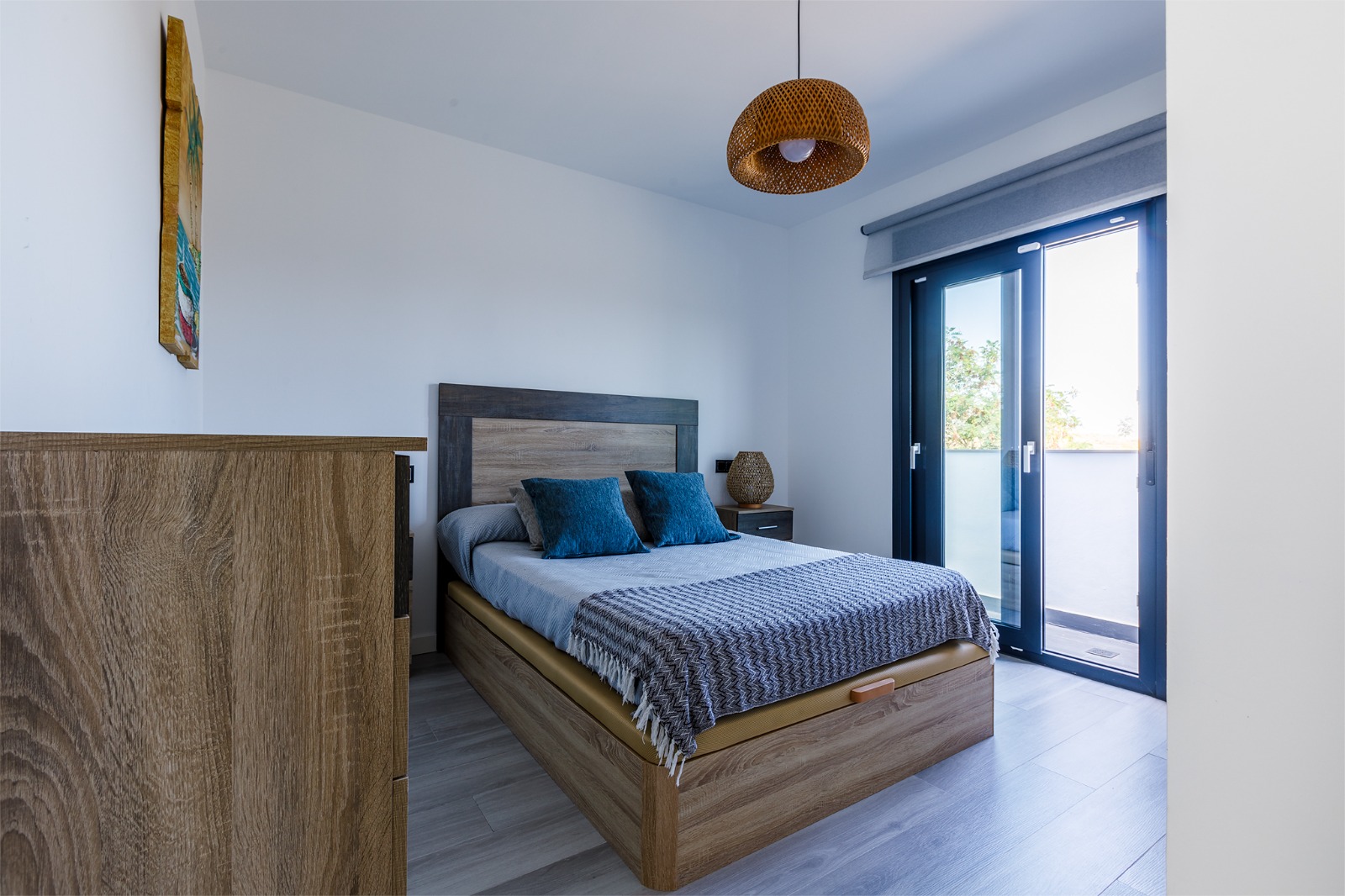 Dormitorio principal con mapamundi de madera, mesitas y lámparas doradas