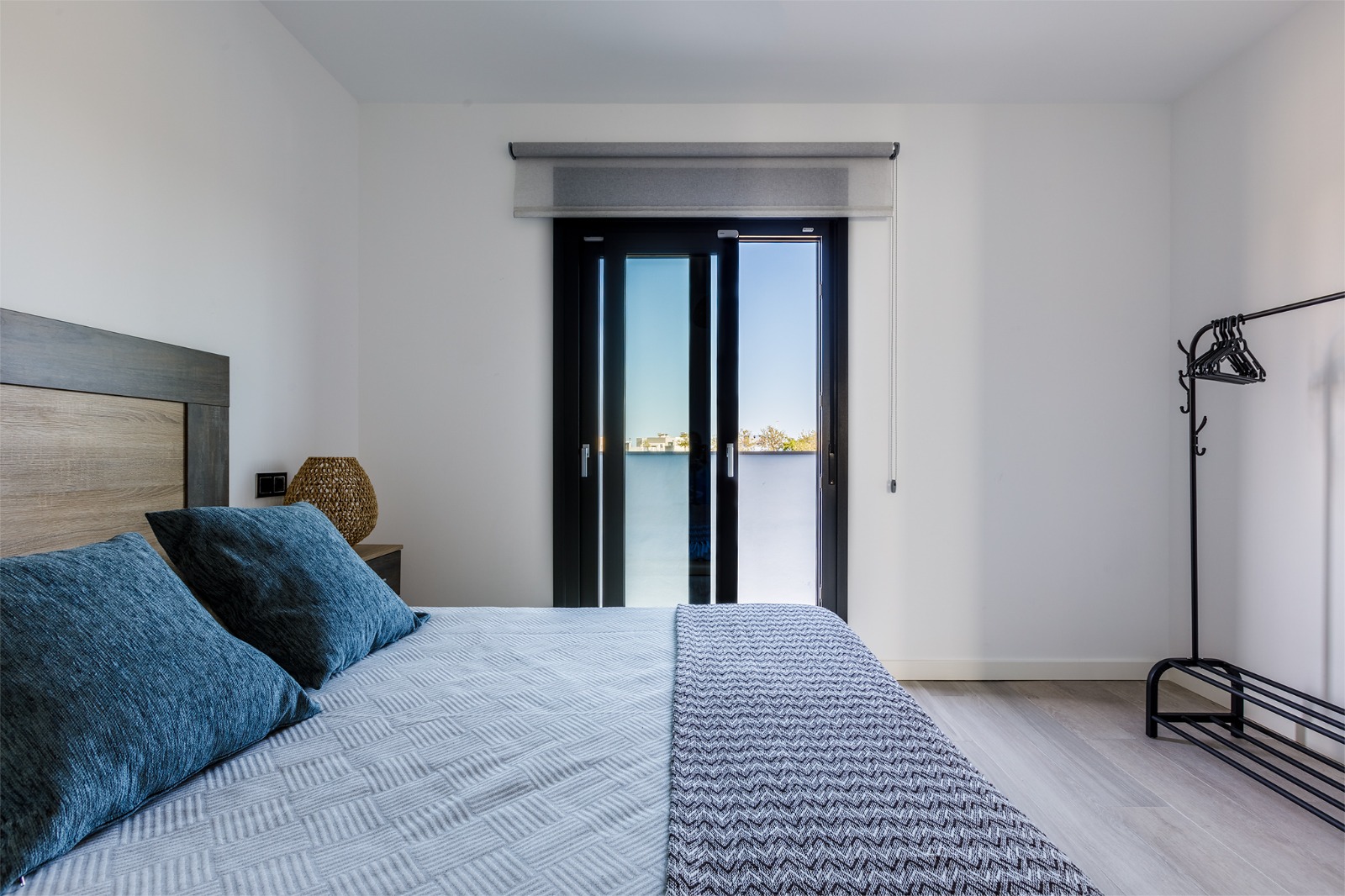 Dormitorio con cama doble, lámpara de mimbre y salida a la terraza