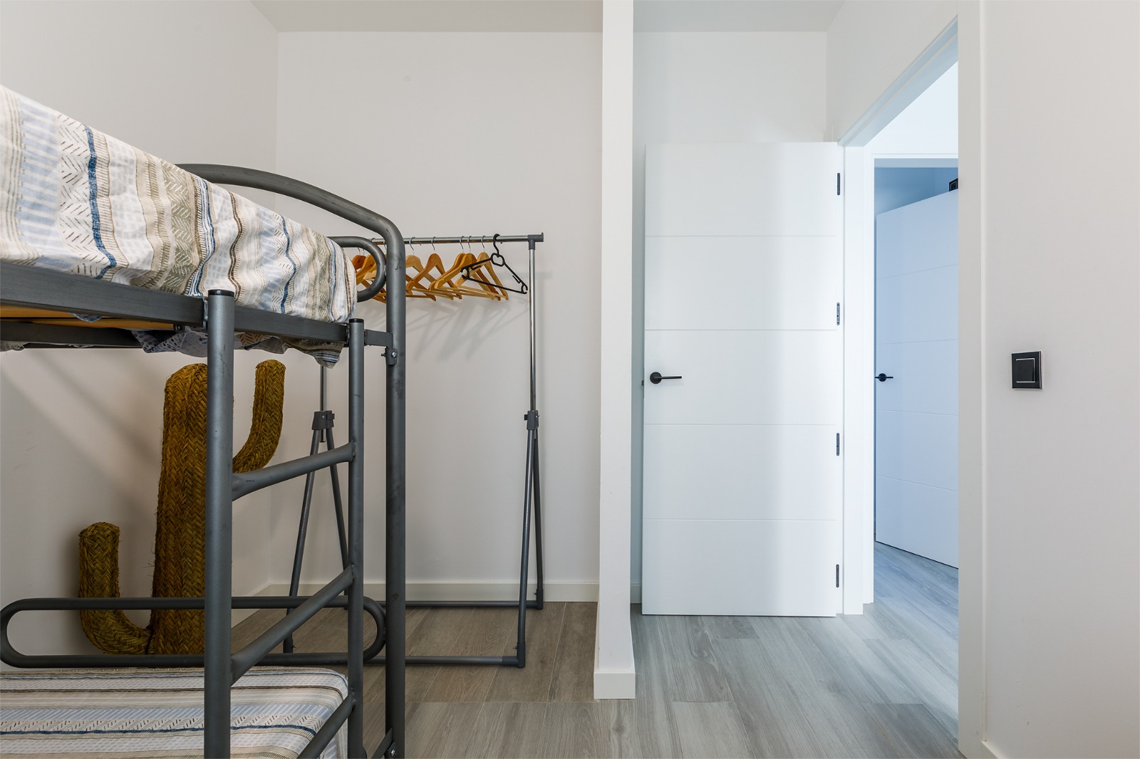 Dormitorio con literas metálicas, escritorio y lámpara colgante