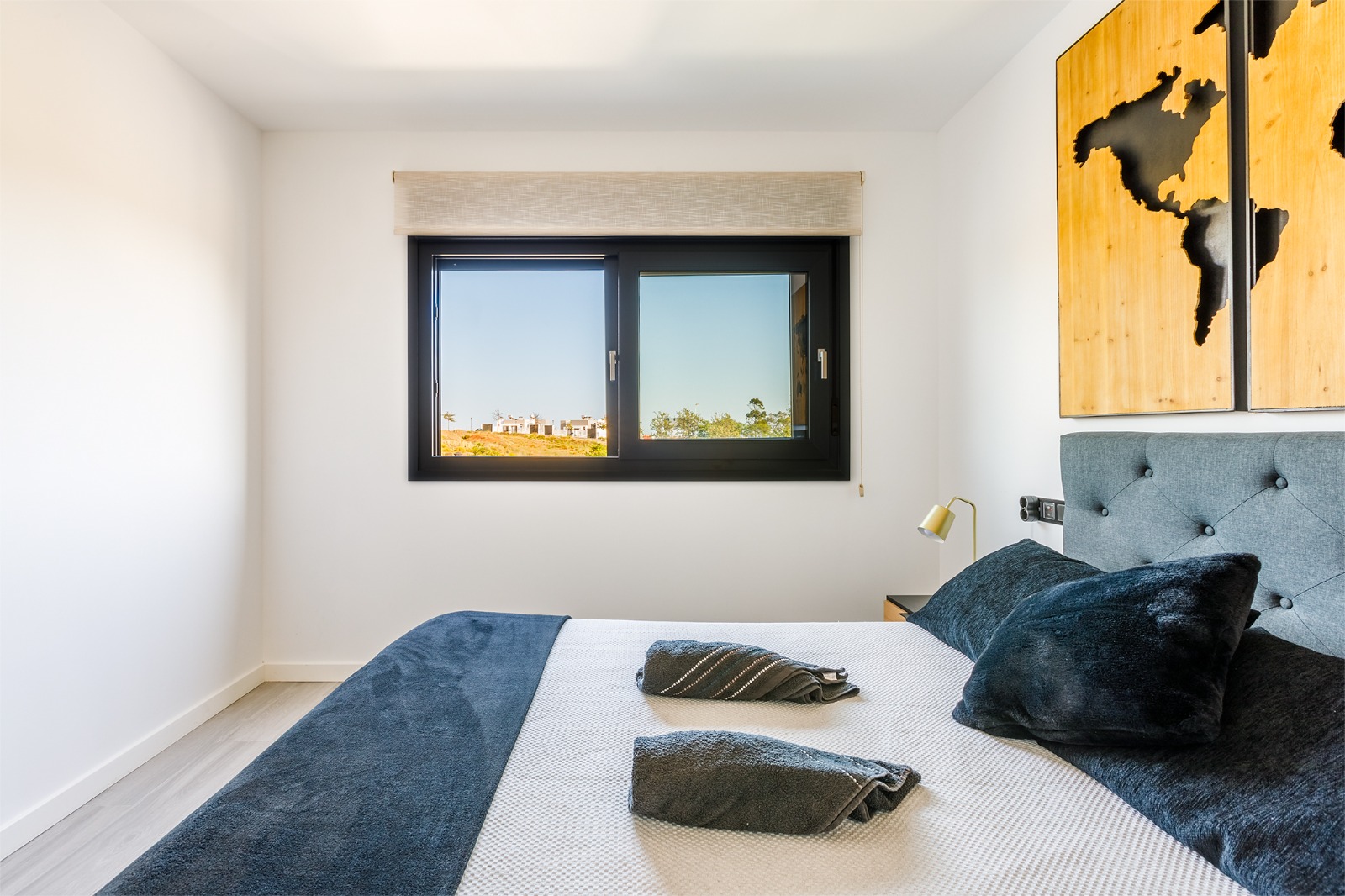Dormitorio con cama doble, cabecero de madera y salida a la terraza