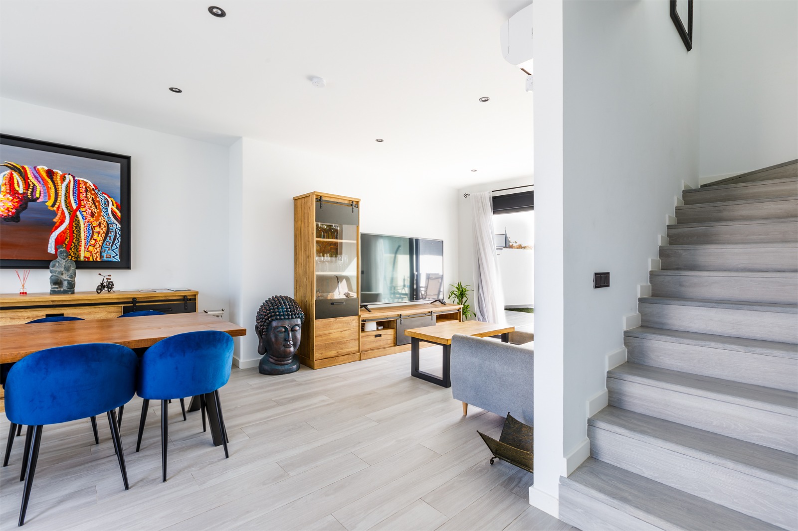 Salón comedor con vitrina de madera, televisión y escalera al piso superior