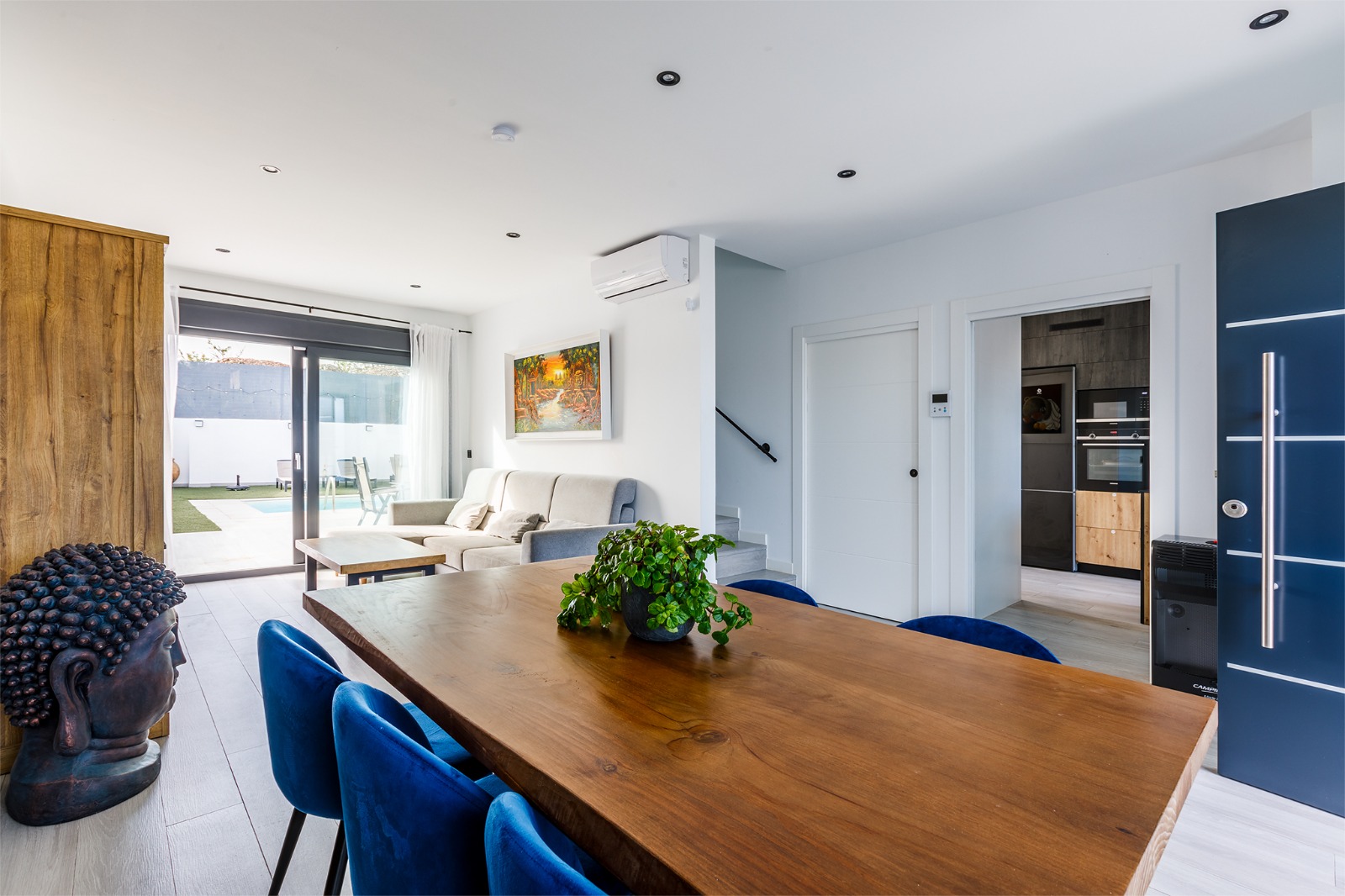 Salón comedor abierto con sofá, mesa de comedor y acceso a la cocina